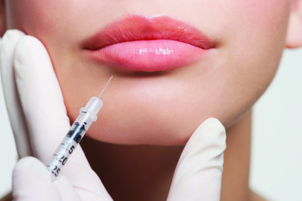 Close up of woman receiving botox injection in lips