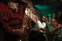 men playing bass, saxophone, and trumpet