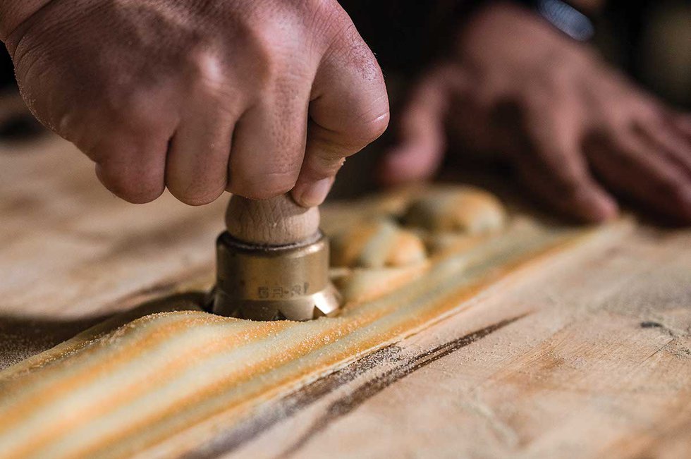 Close up of hands cutting uncooked pasta into shapes