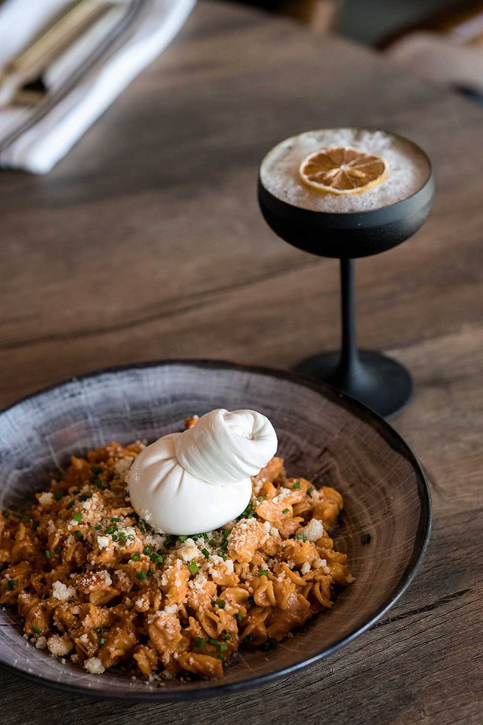 Pasta dish with burrata and martini with orange slice