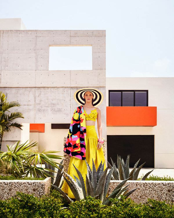 Model posing in front of abstract building, wearing a yellow dress and big hat.jpg