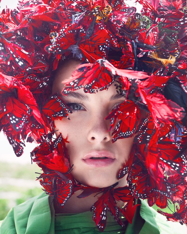 Model posing with red butterfly feathers.jpg