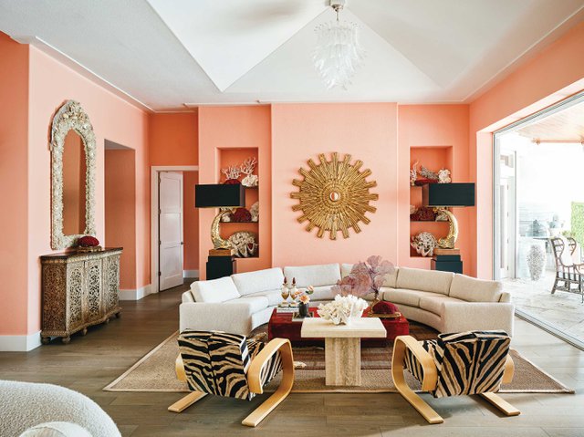 Pink living room with white couch and printed chairs.jpeg