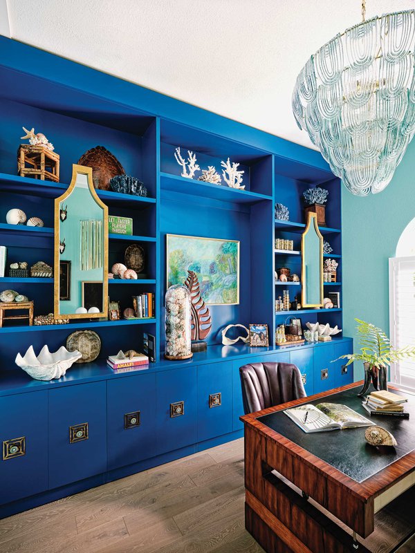 Study room with vibrant blue cabinetry and seashell decor.jpeg