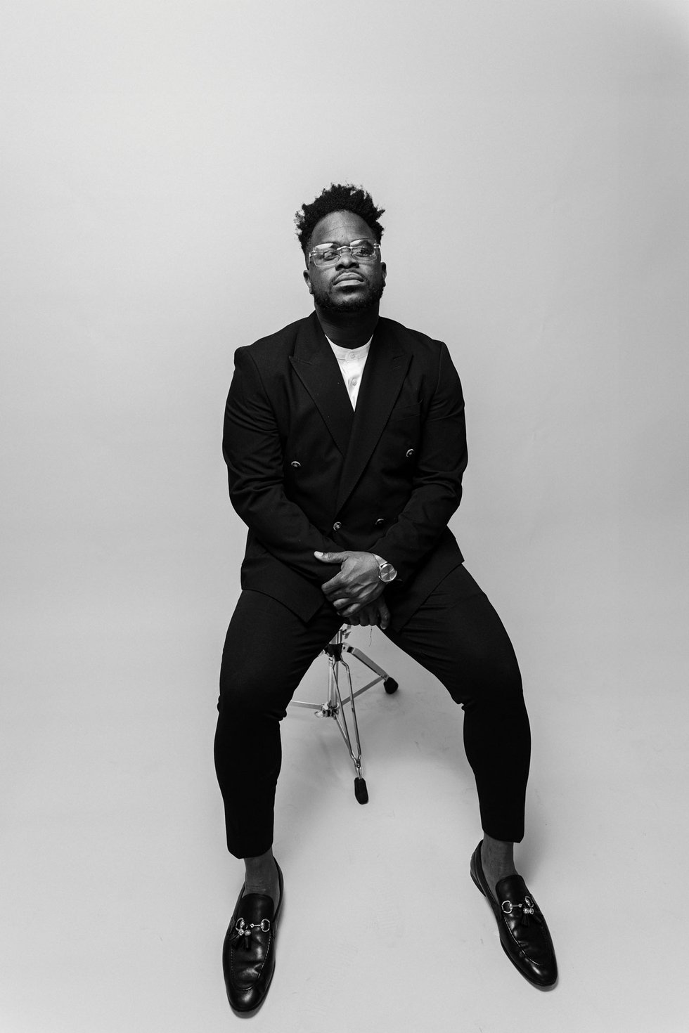 Malike adigun, founder of curate entertainment poses on a chair