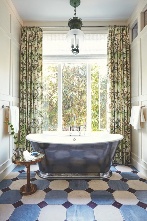 Blue bathtub against window with blue tile floors and green curtains.jpg