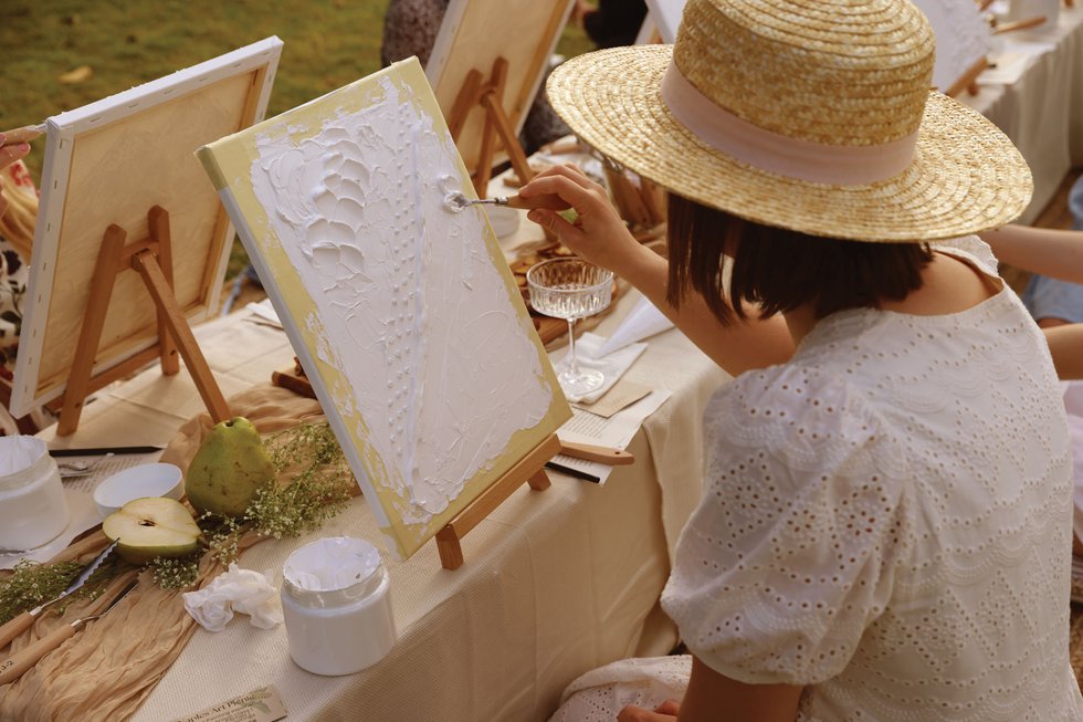 Woman paints on canvas on picnic table setup