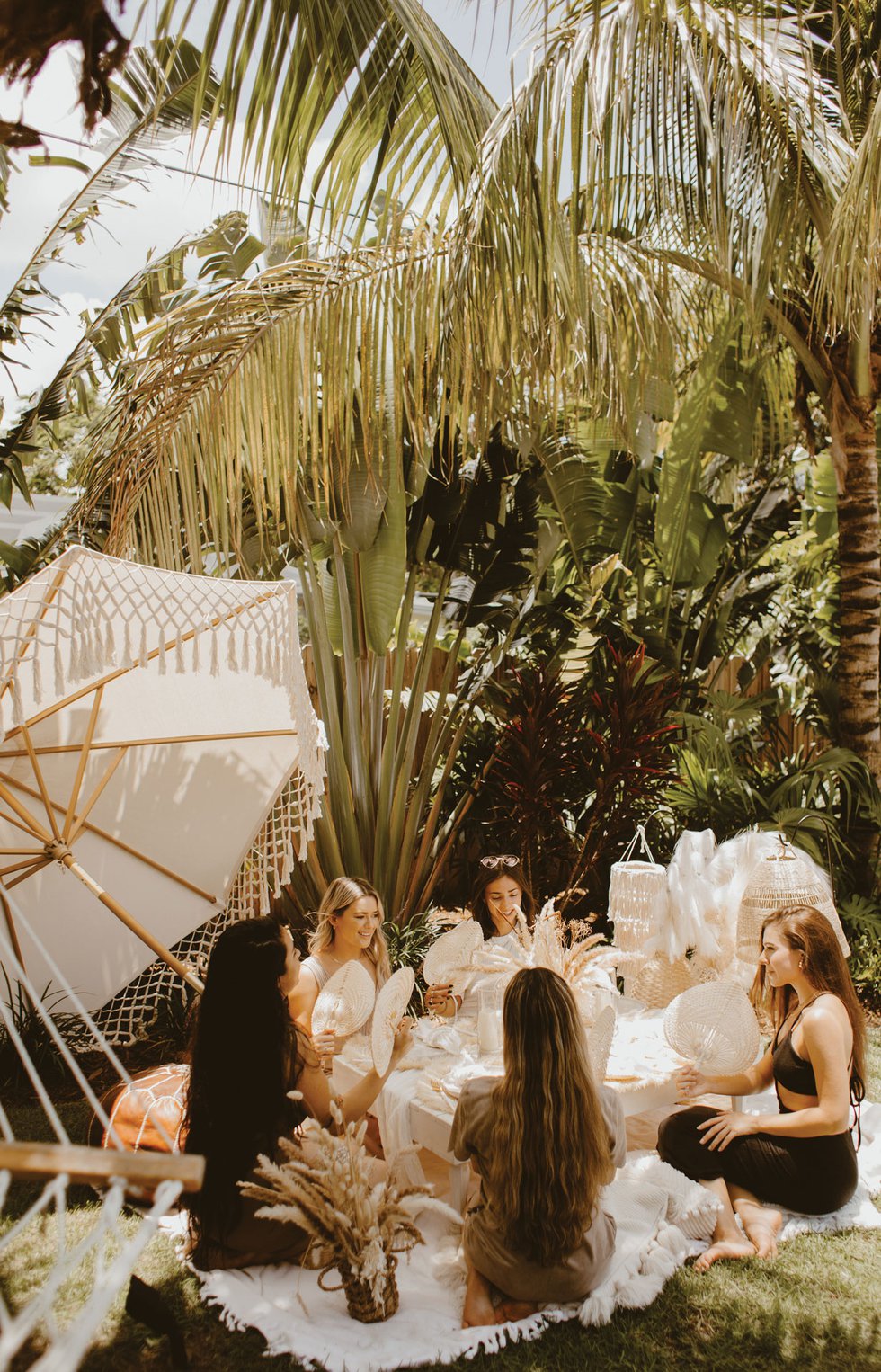 Gathering of partygoers with lush picnic setting with fans and florals