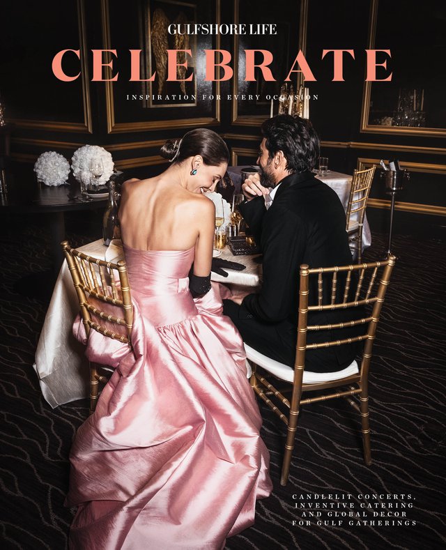 Woman in pink silk gown and man in suit sitting in chairs at a table